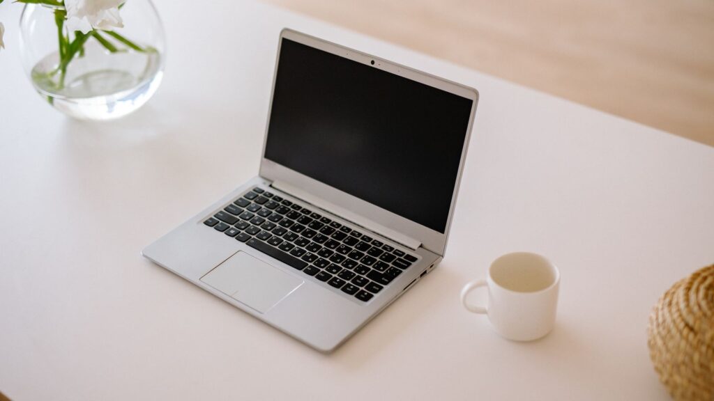 An everyday budget laptop on a bright white desk with a coffee mug