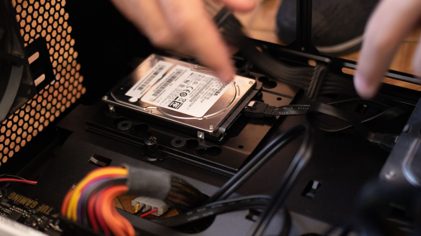 Hands installing a storage drive into a PC case during a build