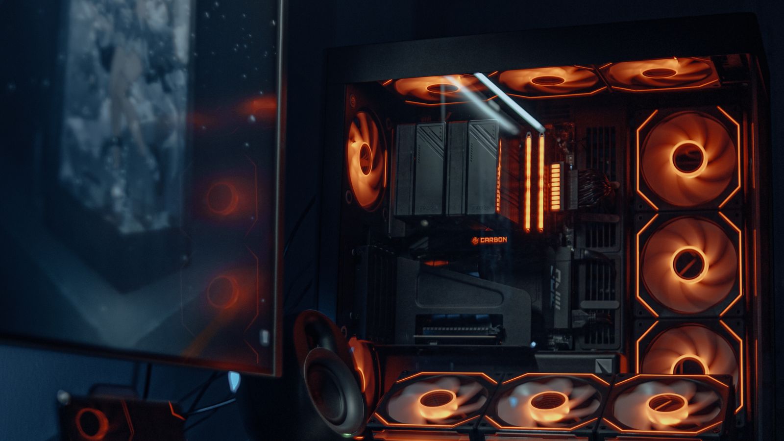 A finished RGB gaming PC build next to a desktop monitor