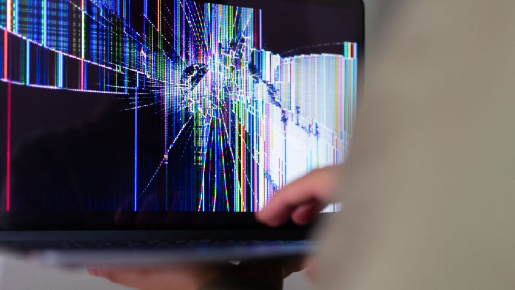 A laptop screen showing colourful glitch, scrambled lines and strange colours, a sign of display artefacts