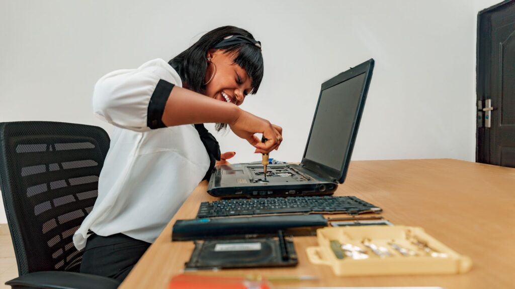 A technician opening a laptop with a screwdriver to check the internal display connection