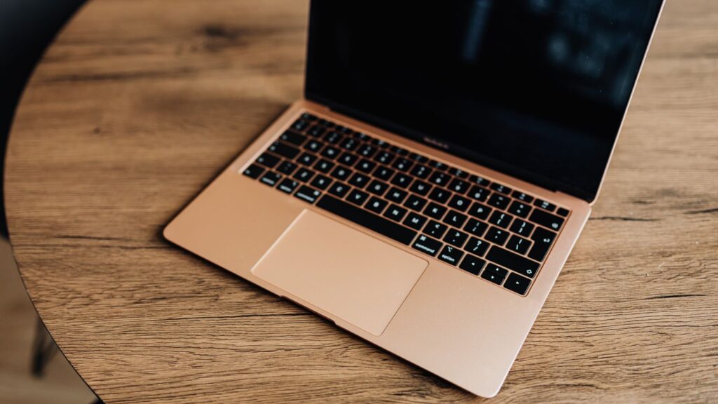 A gold MacBook Air laptop on a wooden table