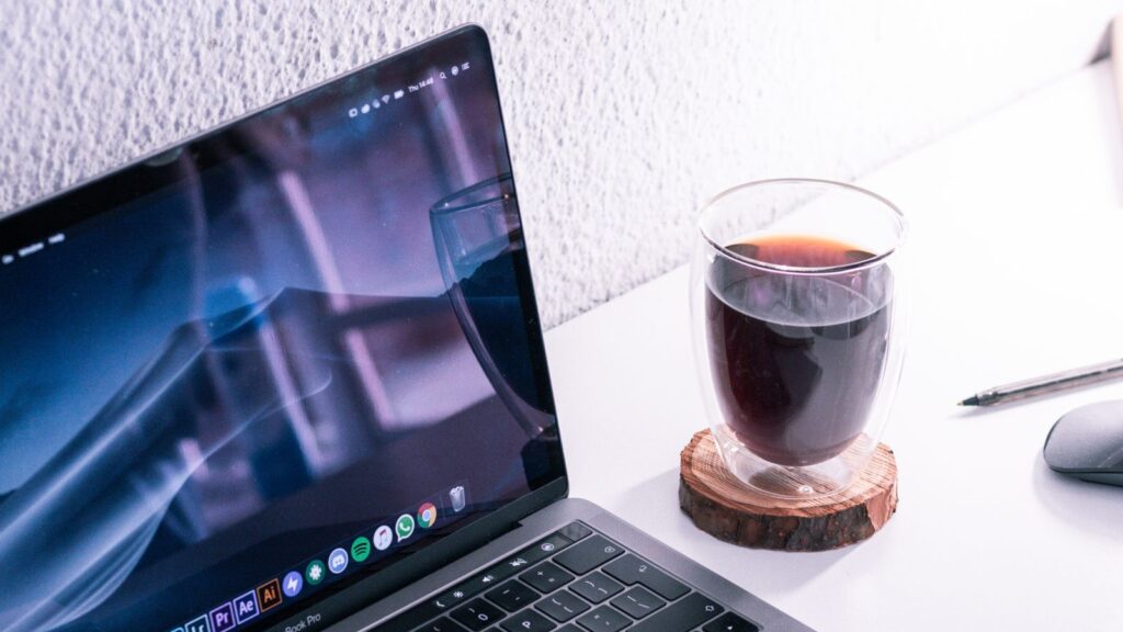 A MacBook Pro running creative apps with a coffee beside it