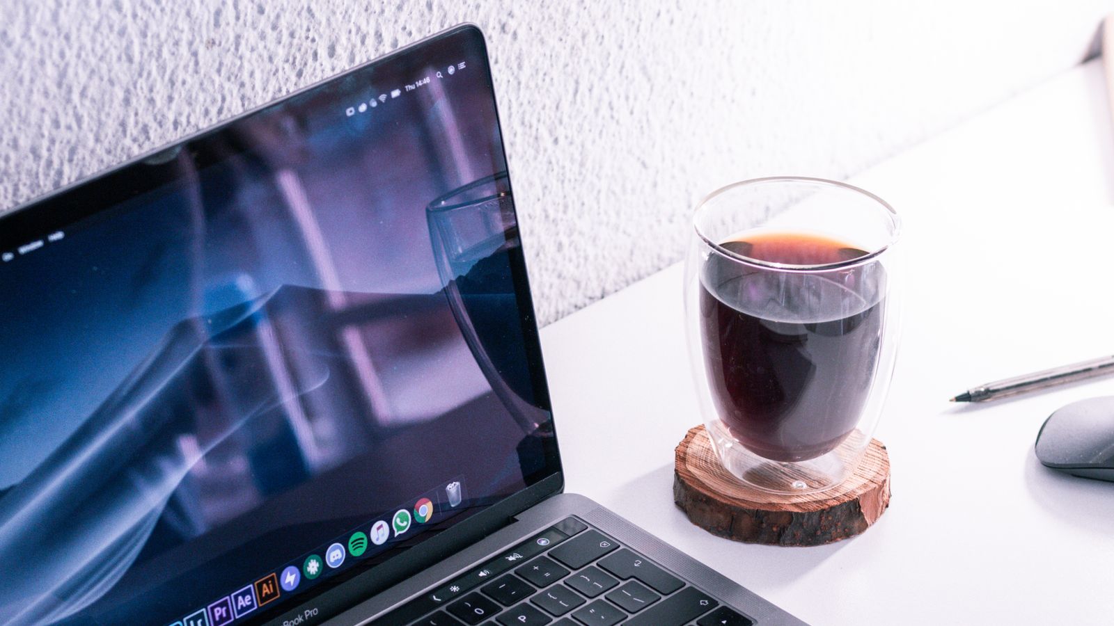 A MacBook Pro running creative apps with a coffee beside it