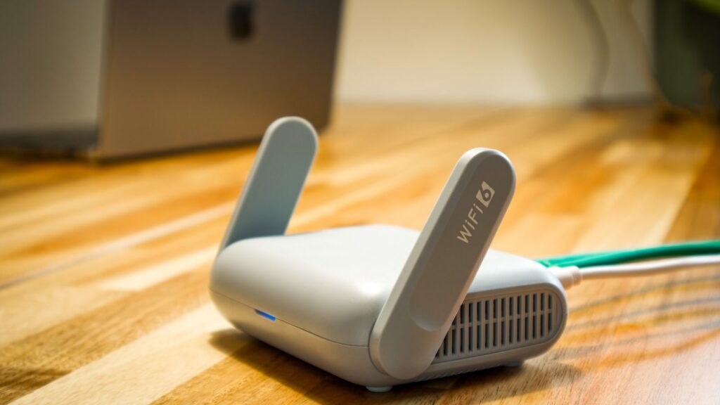 A modern WiFi 6 router with antennas on a wooden desk