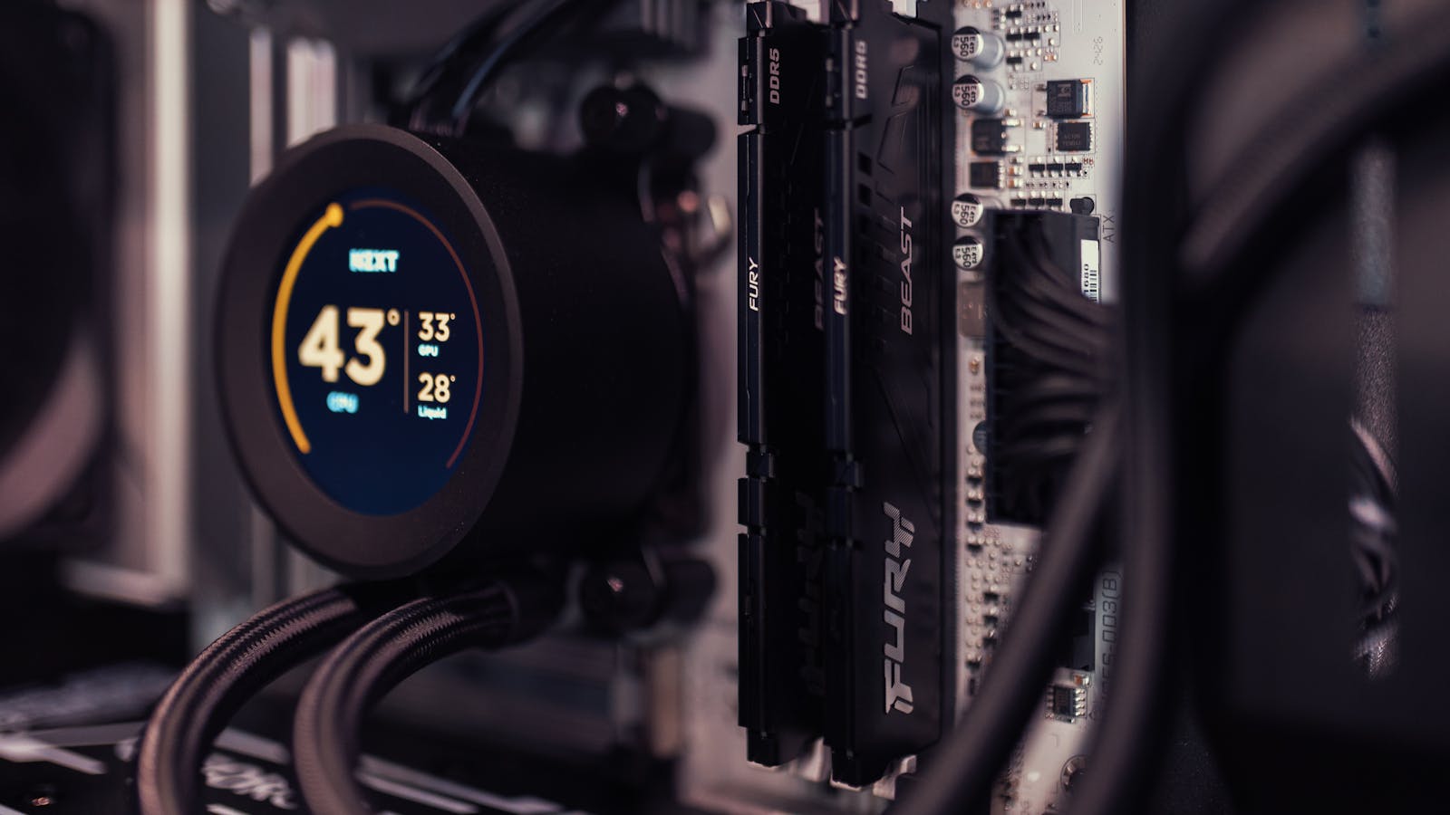 Two Kingston FURY Beast DDR5 sticks installed on a motherboard beside an AIO cooler