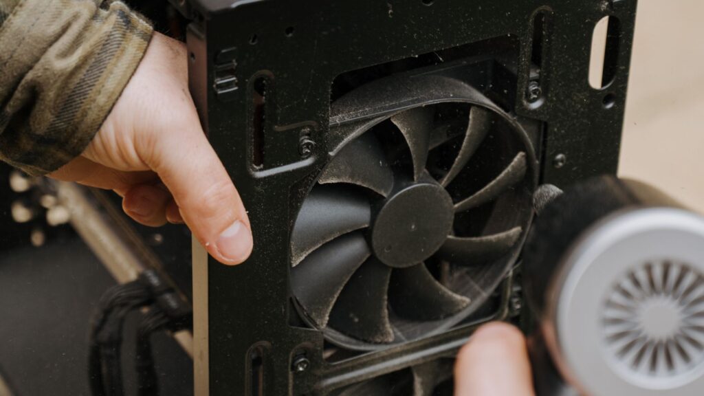 Blowing dust out of a clogged computer case fan with an electric air duster