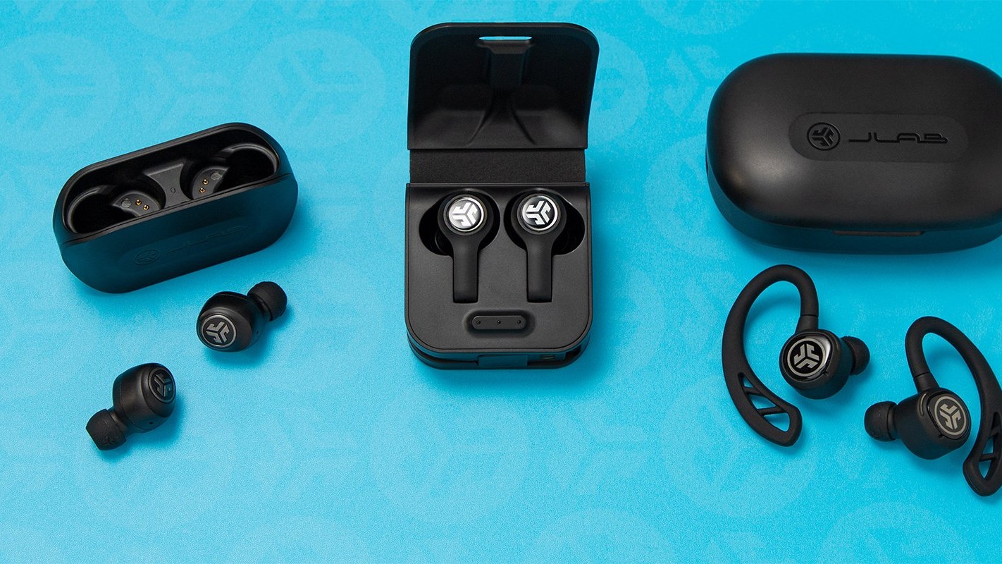 Three pairs of JLab true wireless earbuds with their cases on a blue background