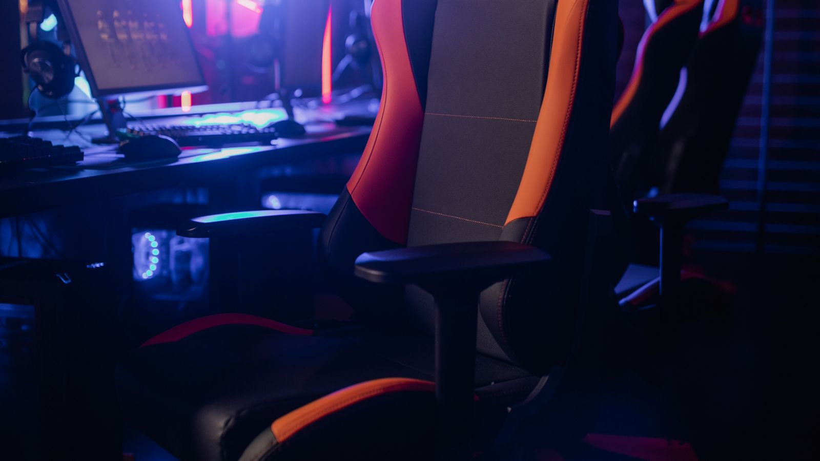 Are Gaming Chairs Bad for Your Back? The Honest Truth (and What to Buy Instead) | Hardvance A racing-style gaming chair with raised side bolsters at a neon-lit gaming desk