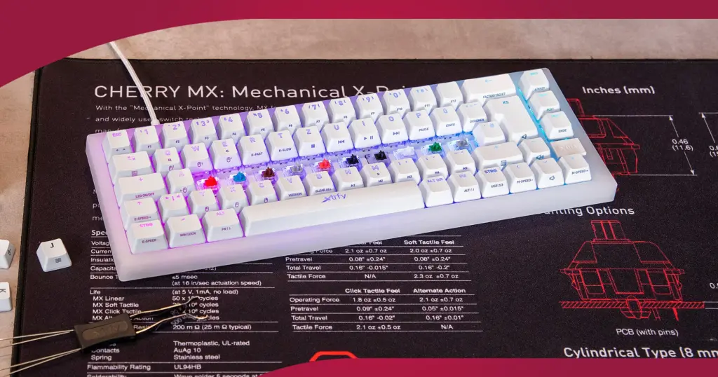A mechanical keyboard with switches removed, resting on a Cherry MX switch specification mat showing durability ratings