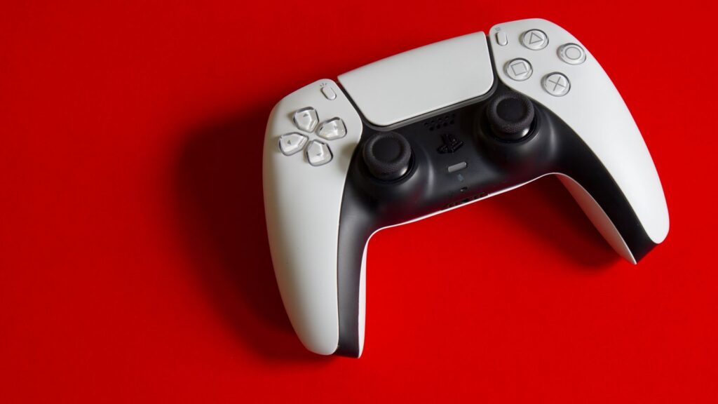 A white PlayStation 5 DualSense controller on a red background