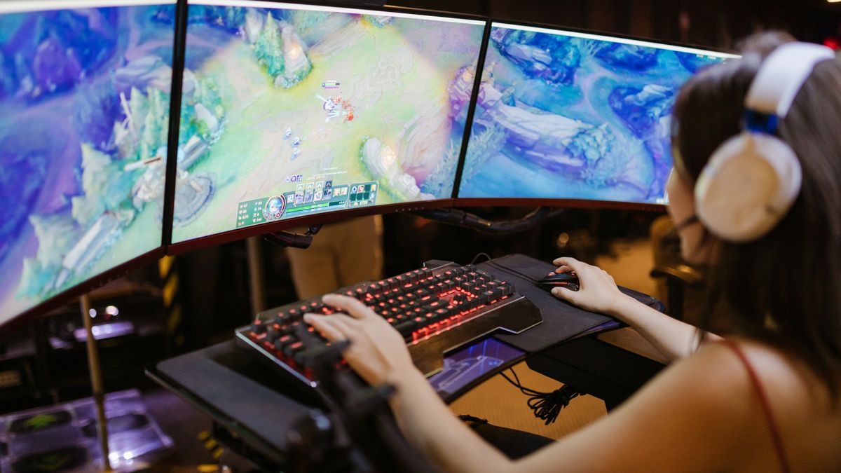 Gamer wearing a gaming headset at a multi-monitor PC setup