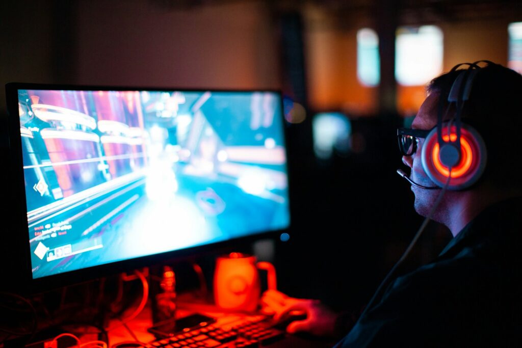Gamer wearing a headset in front of a monitor showing fast motion in a game