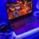 Gaming laptop with RGB keyboard running a game beside a headset and mouse