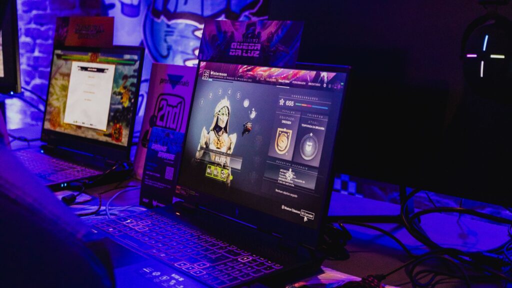 Row of gaming laptops on a desk under purple lighting
