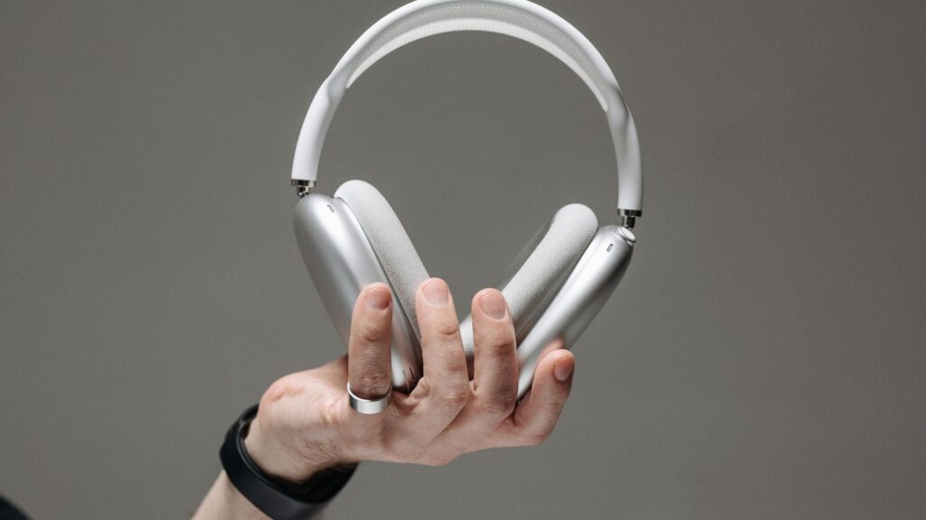 Hand holding silver AirPods Max over-ear noise cancelling headphones