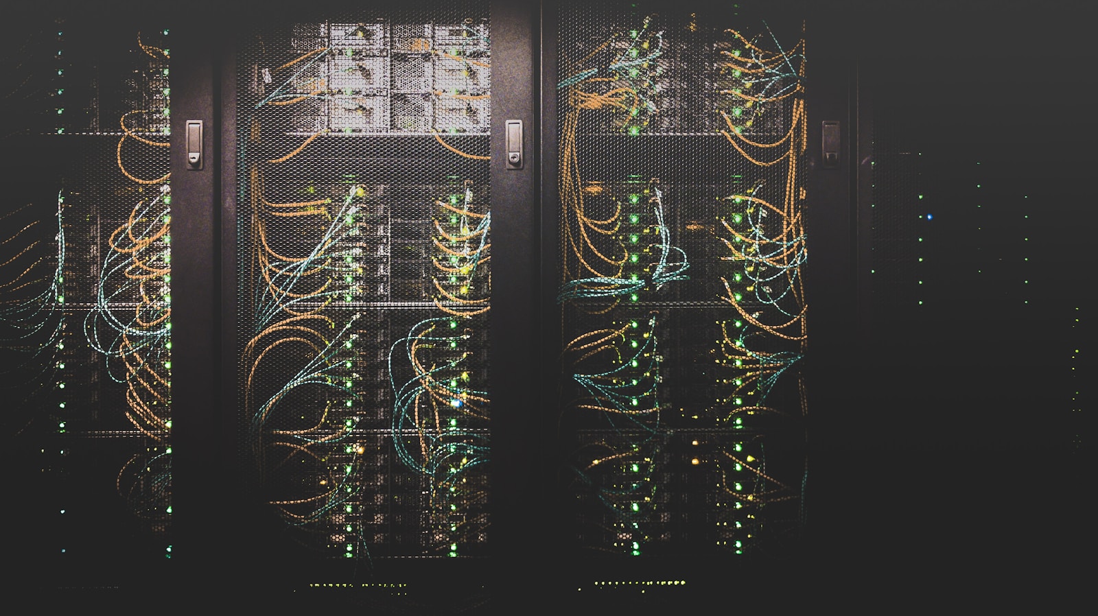 Dark server racks with glowing status lights and cables in a data center