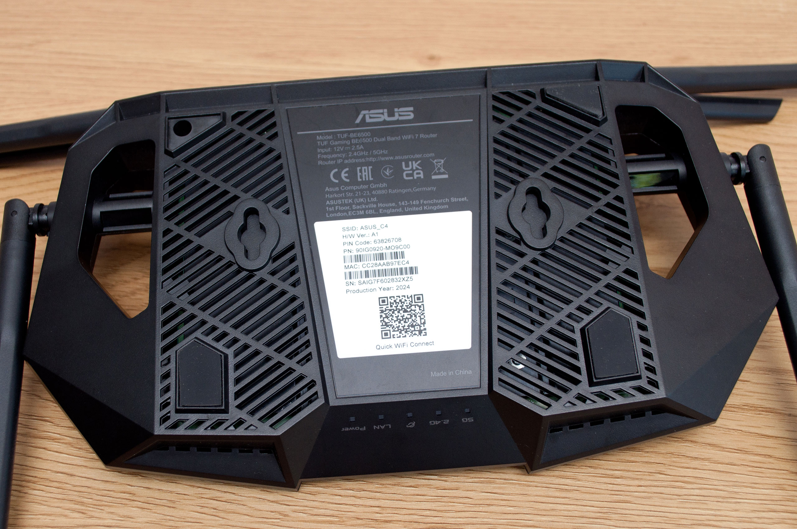 The underside of a WiFi router showing the sticker with default network name, password and QR code