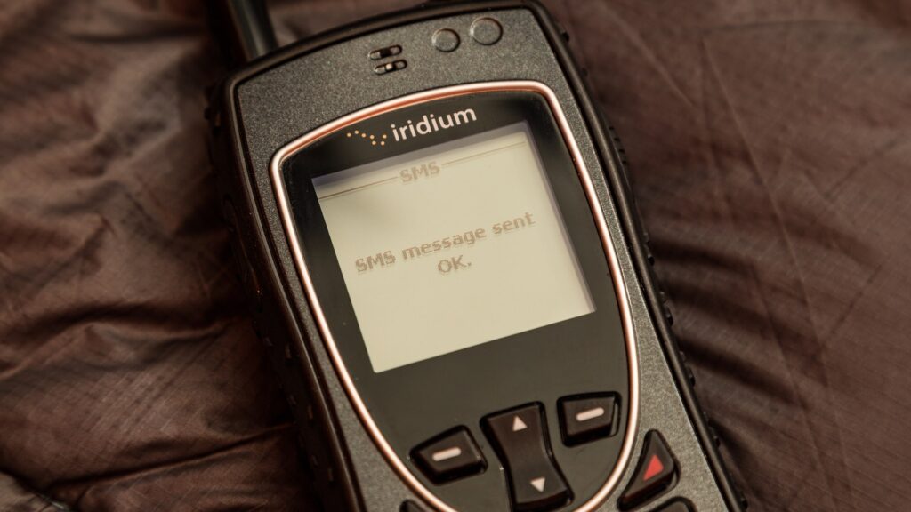 An Iridium Extreme satellite phone with the words SMS message sent OK on its screen