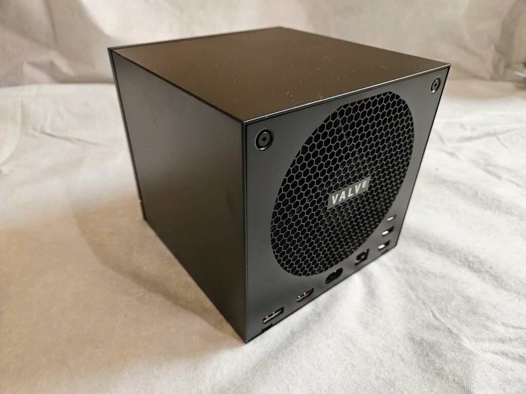 The Valve Steam Machine, a small matte black cube, showing the honeycomb rear fan grille with the Valve logo