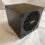 The Valve Steam Machine, a small matte black cube, showing the honeycomb rear fan grille with the Valve logo