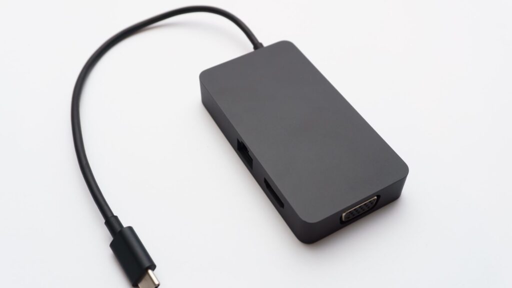 A black USB-C hub with HDMI, Ethernet and VGA ports and a USB-C connector cable