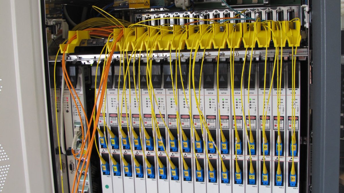 An Alcatel OLT chassis in an exchange, with yellow fibre patch leads running into the line cards.