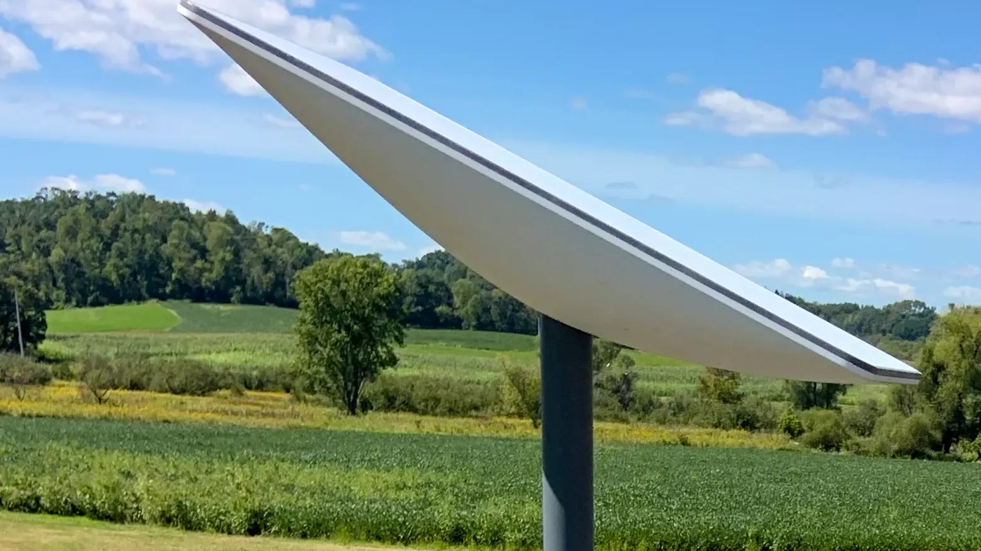 A pole-mounted Starlink dish beside a rural field