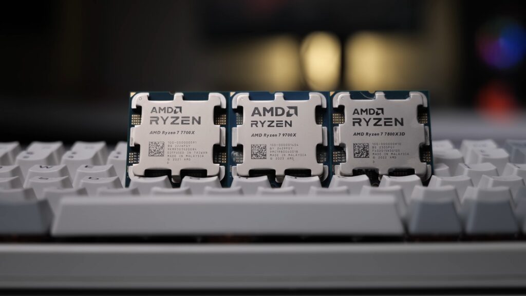 Three AMD Ryzen desktop processors, a 7700X, 9700X and 7800X3D, standing on a keyboard