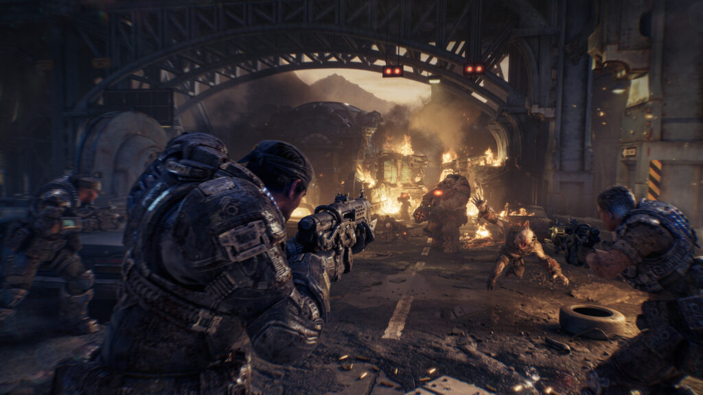 Marcus Fenix and his squad fire at Locust enemies under a burning bridge in Gears of War: E-Day