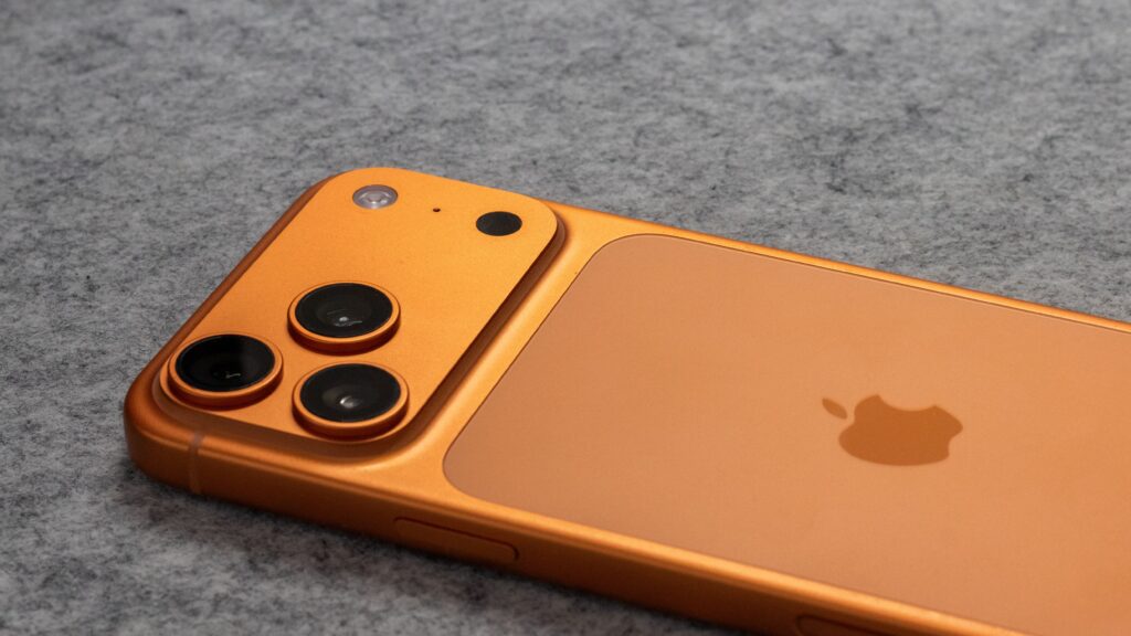 Orange iPhone 17 Pro lying face down on grey felt, showing its triple camera plateau