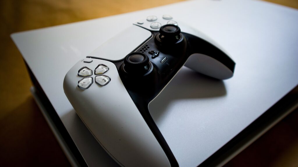 White DualSense controller lying on top of a PS5 console
