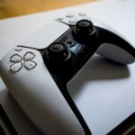 White DualSense controller lying on top of a PS5 console