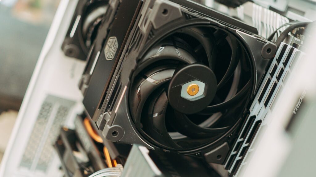 Black tower CPU air cooler with a large fan installed inside a white PC case