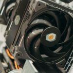 Black tower CPU air cooler with a large fan installed inside a white PC case