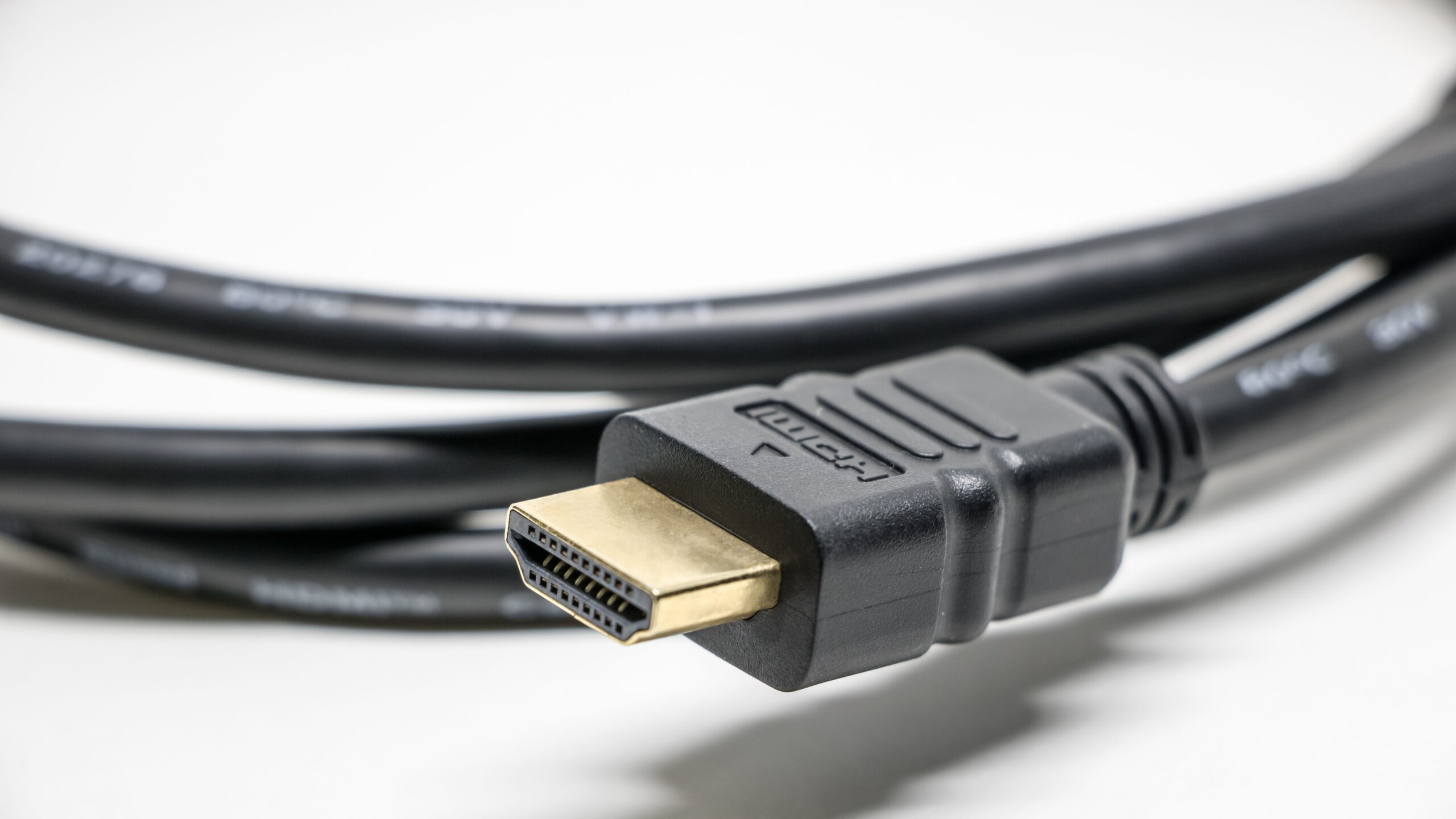 Close-up of a black HDMI cable plug with its gold-plated connector on a white background