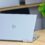 HP convertible laptop open on a wooden desk next to a green plant, seen from behind