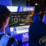 Gamers playing on a monitor at a PlayStation 5 gaming event with the PS5 logo above the screen