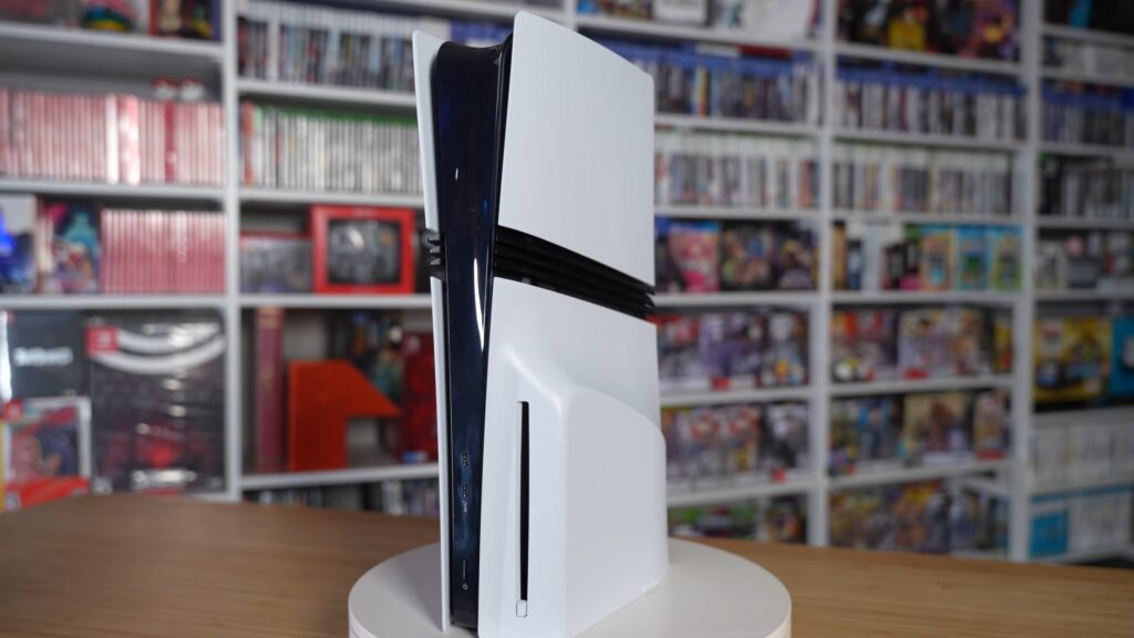 PS5 Pro console standing upright on a turntable in front of shelves of video games