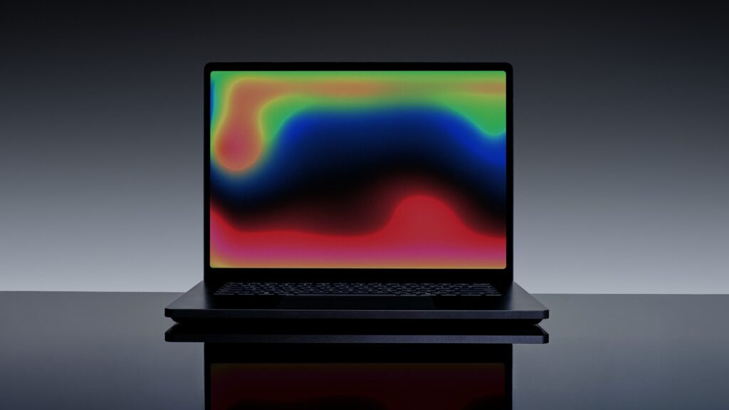 Microsoft Surface Laptop Ultra in dark Nightfall finish, open with a colourful screen, on a reflective surface